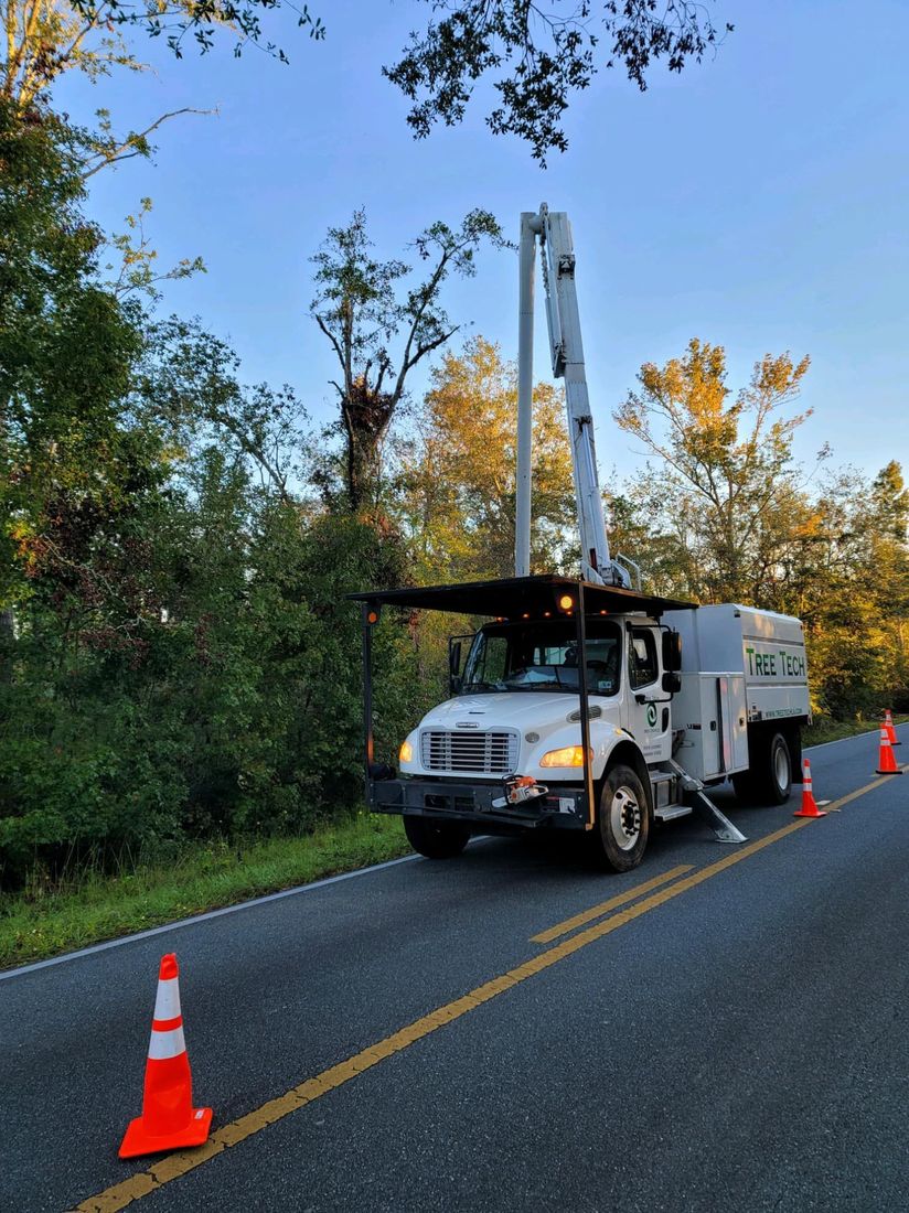 Tree Tech of Louisiana bucket truck staged with cones on a two-lane road — tree service in Covington, LA